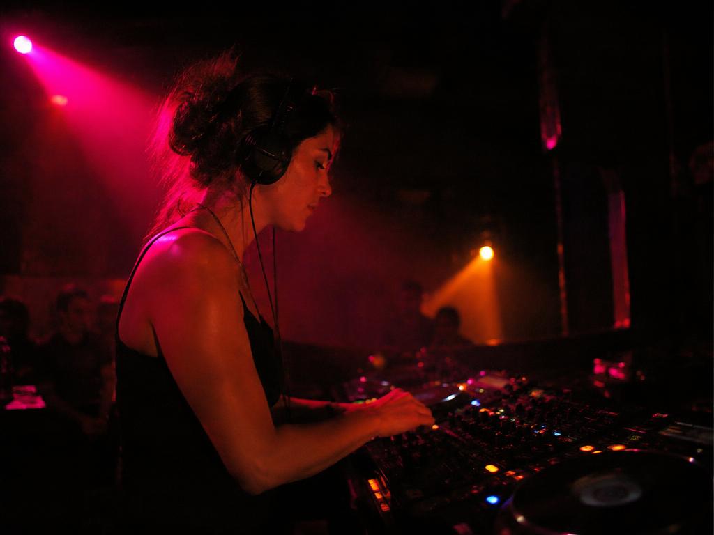 DJ performing at the decks in pink stage light